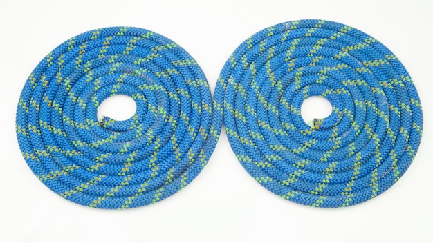 Durable colored rope for climbing equipment on a white\
background. coil of braided cable. item for tourism and travel