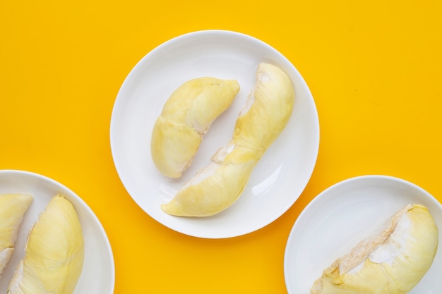 Durian in white plates on yellow background.