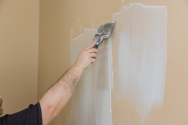 Photo during room renovation in worker plastered the plasterboard wall