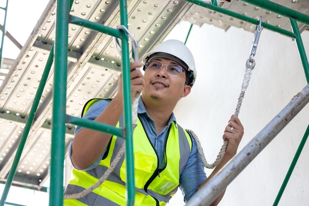 During work at a height, a construction worker wears a safety\
harness belt. on a background of a drilling platform for a\
structural rig