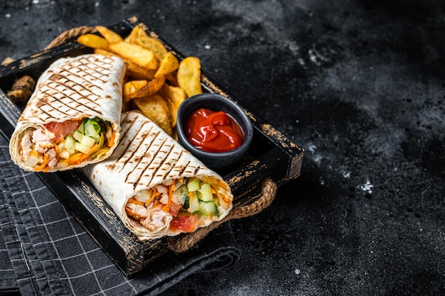 Durum doner kebab or Shawarma with meat vegetable salad and french fries Black background Top view Copy space