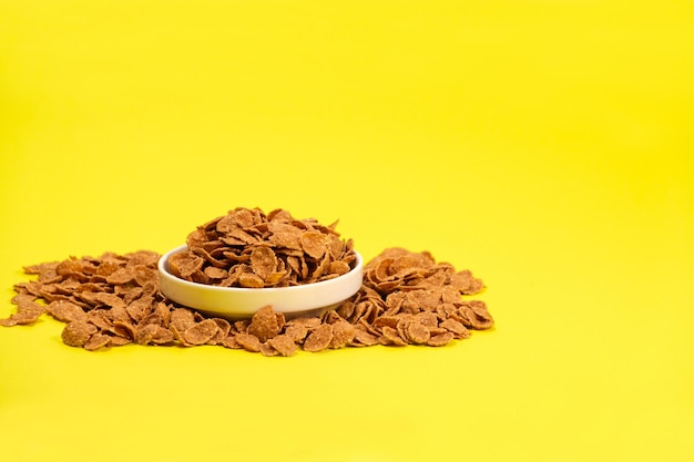 Durum wheat flakes quick breakfast cereal on a plate on a yellow background space for text
