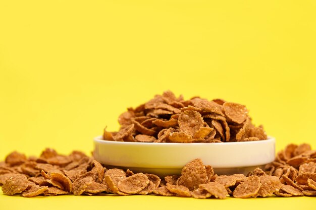 Durum wheat flakes quick breakfast cereal on a plate on a yellow background space for text