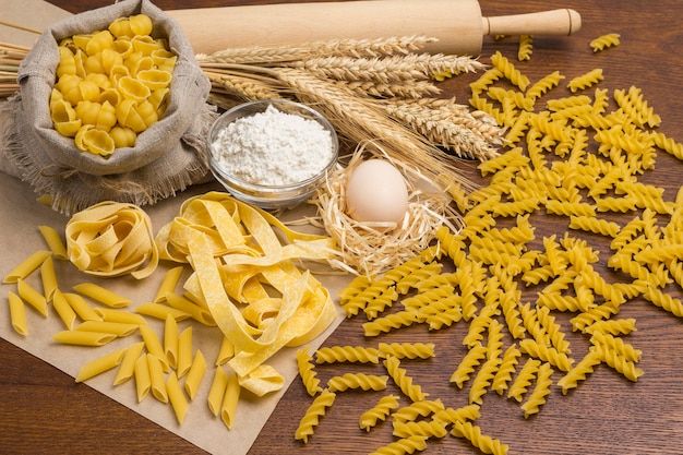 Durum wheat pasta.  Eggs and flour, rolling pin and sprigs of wheat on table