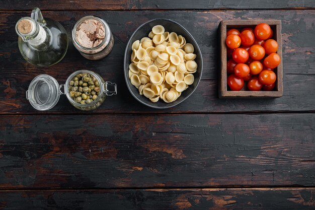 Durum wheat semolina tuna pasta ingredients, on dark wooden background, flat lay  with copy space for text