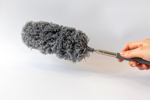 Photo dust collector brush gray in a woman's hand on a white background