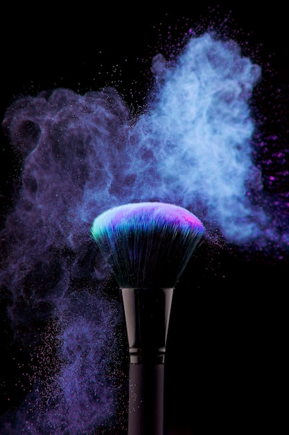 Dust of powder and makeup brush on black background