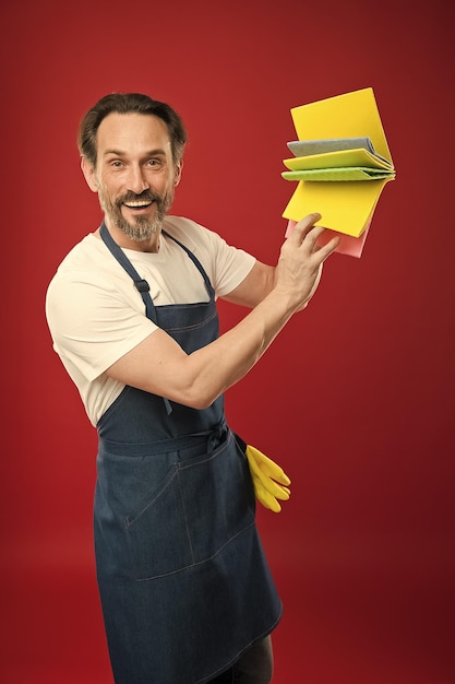 For dusting surfaces Mature man holding cleaning cloths of assorted colors Eldery housekeeper presenting cleaning towels Senior man in apron with rubber gloves Household worker Household service