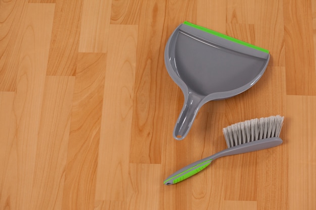 Dustpan and sweeping brush on wooden floor