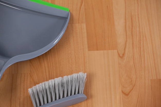 Dustpan and sweeping brush on wooden floor