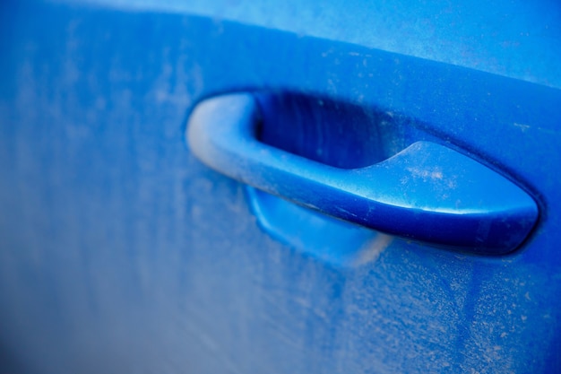 Dusty and dirty door handle of a blue car