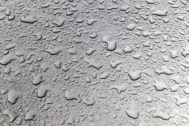 Dusty drops of water on the glass and hood of a car