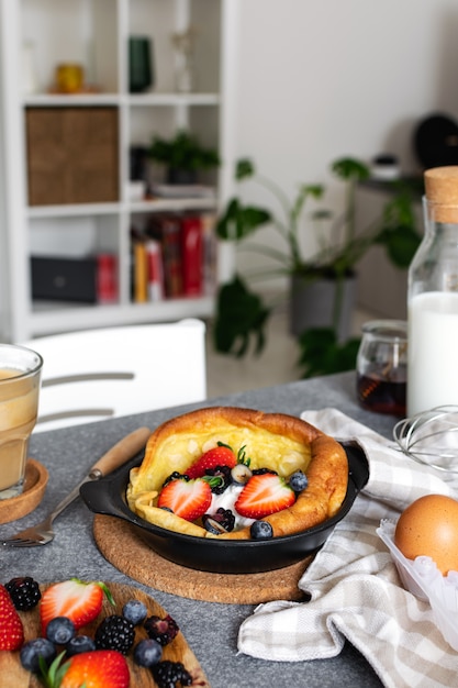 Dutch baby pancake with fresh berries, cup of cappuccino