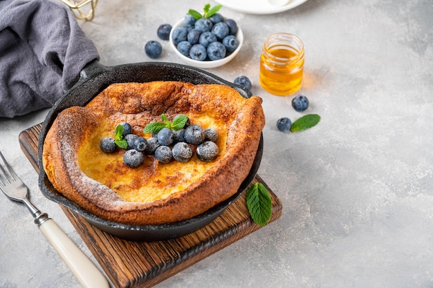 Dutch Baby pancake with fresh blueberries mint and sprinkled with icing sugar Copy space