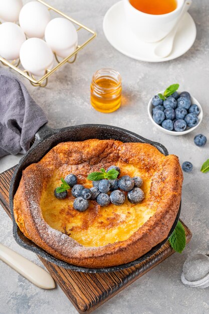 Dutch Baby pancake with fresh blueberries mint and sprinkled with icing sugar in iron skillets