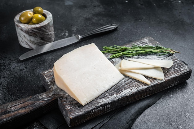 Dutch goat cheese sliced on a wooden cutting board Black background Top view