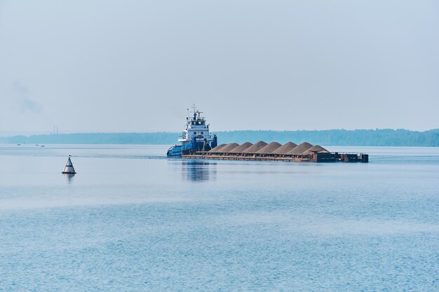 Duwsleepboot duwt droge bulkladingschuit met zand op de rivier in de ochtendnevel