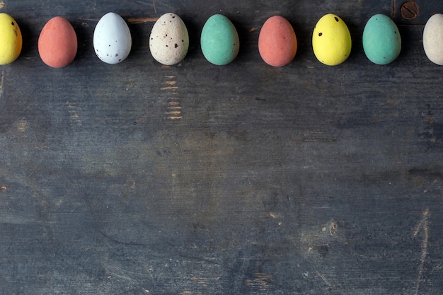 Dyed colorful easter eggs in a row on a vintage wooden background texture, soft pastels modern design