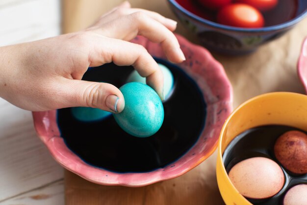 Dyeing eggs for Easter holidays Woman holding a blue Easter egg