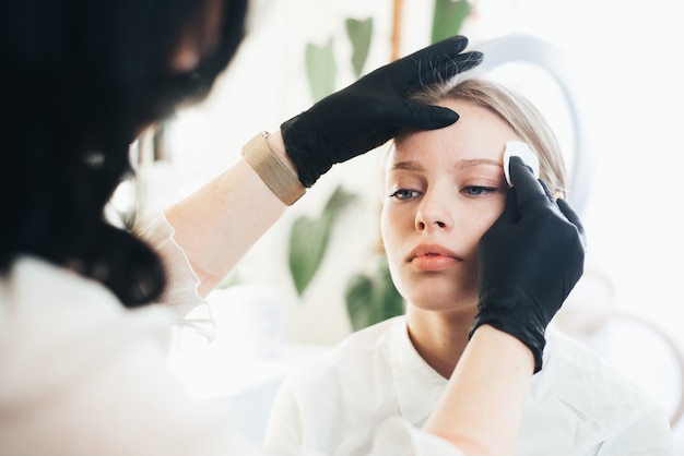 Dyeing and shaping of eyebrows. girl in a beauty salon.