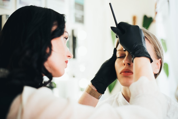 Dyeing and shaping of eyebrows. girl in a beauty salon.