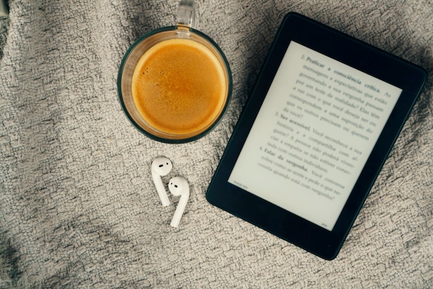 Foto e-book reader, een kopje koffie en een koptelefoon.