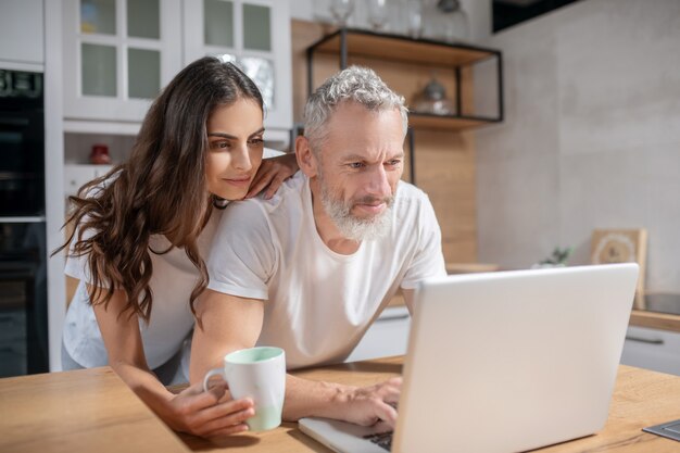 E-mails bekijken. een vrouw die haar echtgenoot omhelst terwijl hij mails controleert