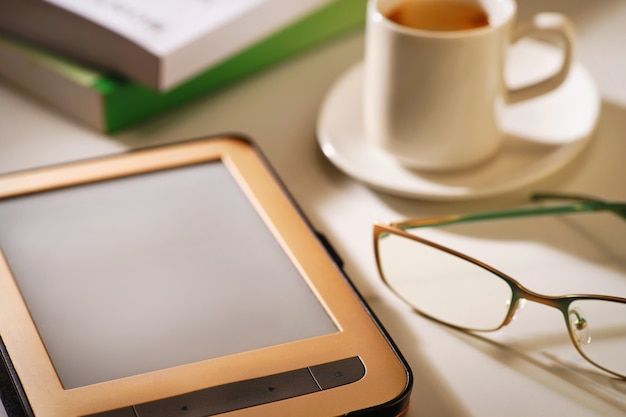 Foto e-reader con tazza di caffè e bicchieri