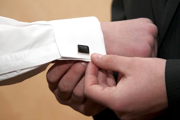 Each wears cufflinks on the sleeves of the groom