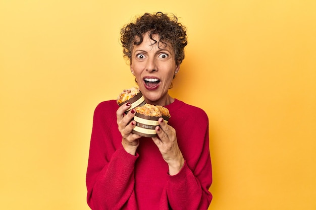 Foto donna desiderosa che cerca muffin su uno sfondo giallo vivace per studio