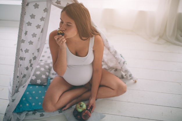 ealthy Zwangere vrouw fruit eten in de kinderkamer in de kinderkamer.