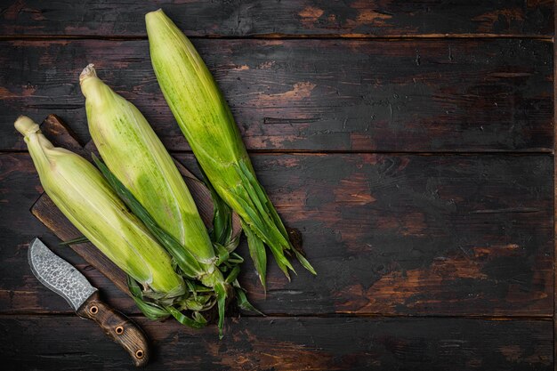 Ear of maize or corn on old dark wooden table background top view flat lay with copy space for text