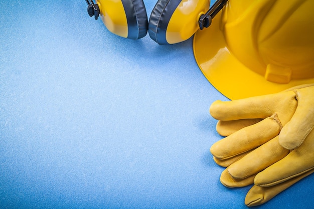 Ear muffs leather safety gloves building helmet on blue background construction concept.