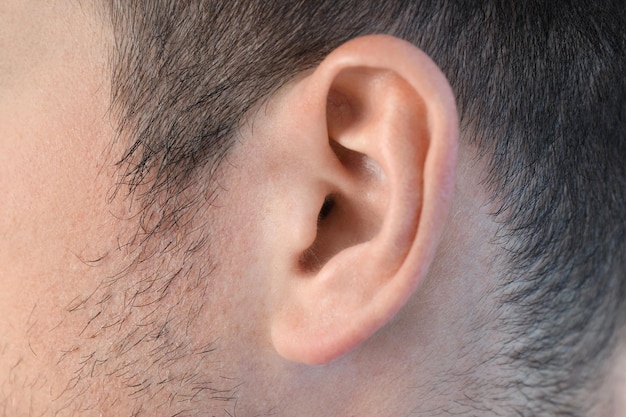 Ear of young man all over background, close up