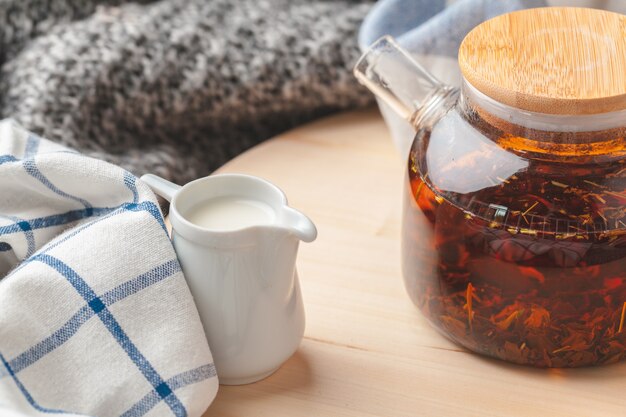 Photo earl grey tea in glass tea pot on wood plate close up