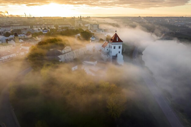 中世の城と広い川の近くの旧市街と歴史的建造物を見下ろす遊歩道の早朝の霧の朝と空中パノラマビュー