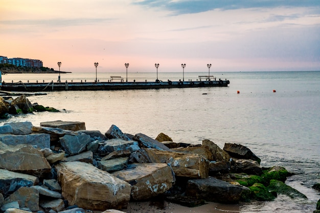 Early morning, sunrise over sea. Pier on the concrete embankment