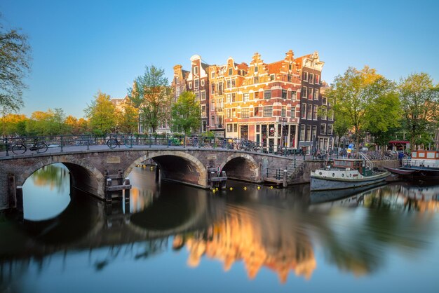 Early quiet morning in Amsterdam Gentle sun shines the famous view of Amsterdam Typical old houses and bridges