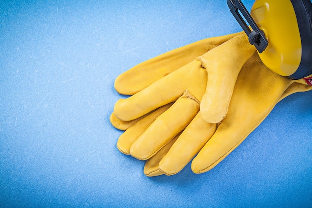 Earmuffs leather safety gloves on blue background construction concept