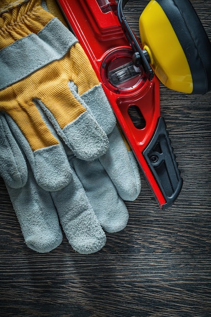 Earmuffs safety gloves construction level on wooden board