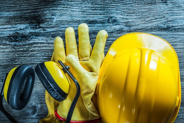 Photo earmuffs safety gloves hard hat on wooden board