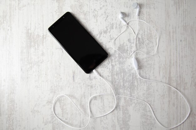 Earphone with smart phone on table background