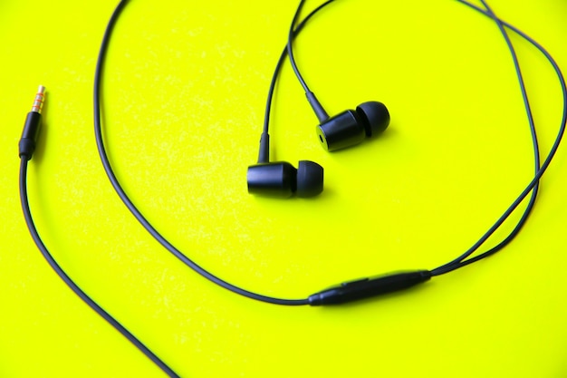 Earphones lying on the green background. modern music concept. audio technology