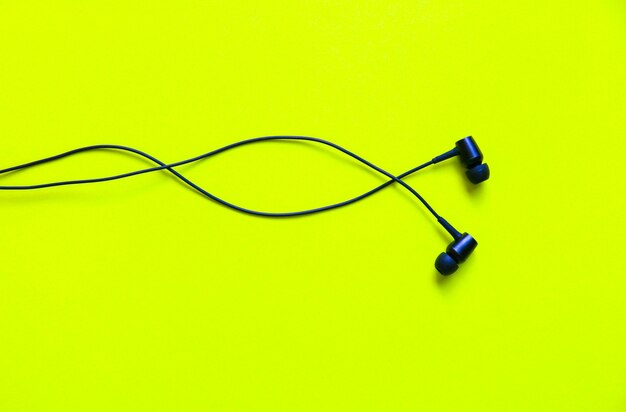 Photo earphones lying on the green background. modern music concept. audio technology.