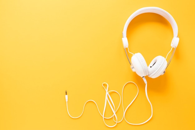 Earphones on yellow background with copy space