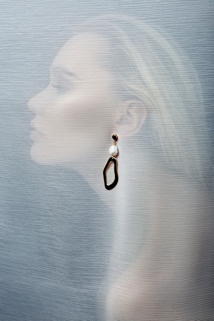 earring in the ear of a woman inserted through transparent fabric