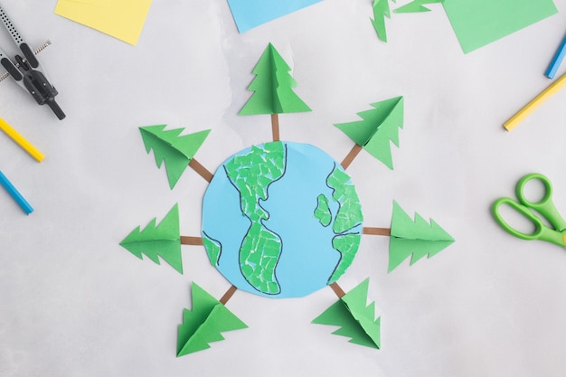 Earth cut from paper around trees earth day concept kids paper craft high quality photo