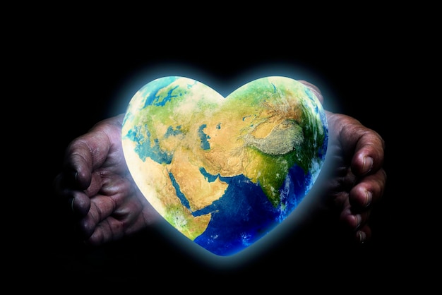 Concetto della giornata della terra mani che tengono il globo a forma di cuore su sfondo nero