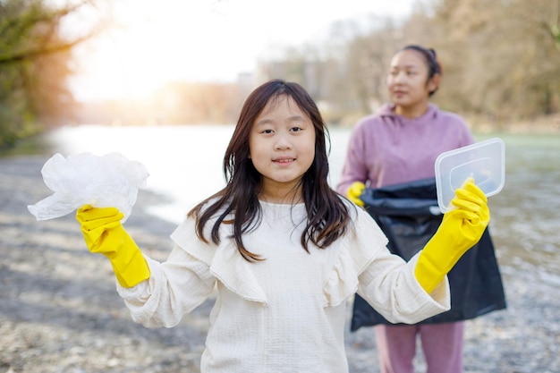 Earth Day-concept Vrouw en dochter halen afval op in vuilniszakken opruimen in de natuur tot recycling in hun gemeenschappen maken rivier schoon en beschermen het milieu tegen vervuilingsbehoud Natuur