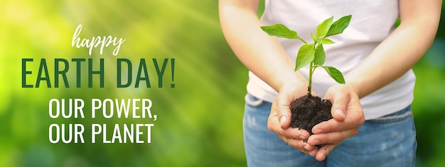 Earth Day green sprout in female hands on green background with text